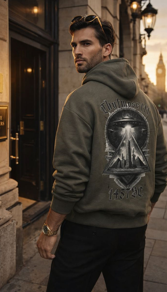 Man wearing a hoodie with a design on the back, standing on a city street.