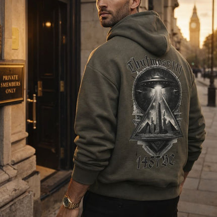 Man wearing a hoodie with a design on the back, standing on a city street.
