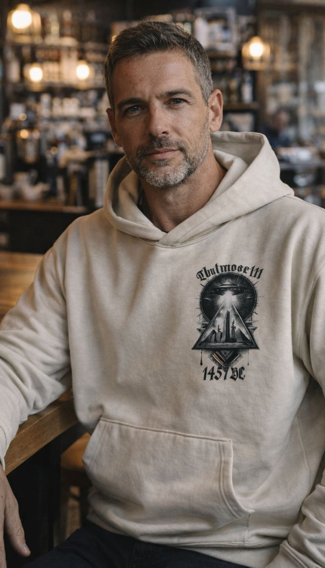 Man wearing a beige hoodie with a graphic design in a bar setting