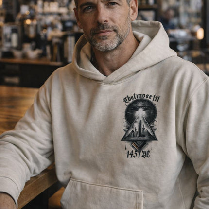 Man wearing a beige hoodie with a graphic design in a bar setting