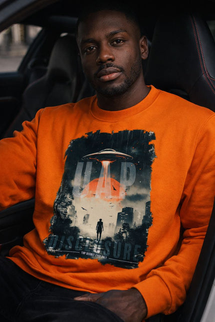 Man wearing an orange sweatshirt with a graphic design inside a car.